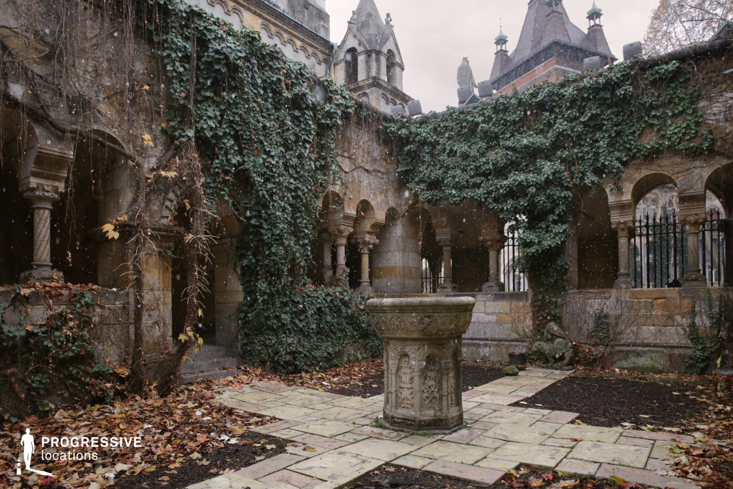 Ivy-covered arched courtyard with central stone feature, film and photography location with enclosed historic architecture