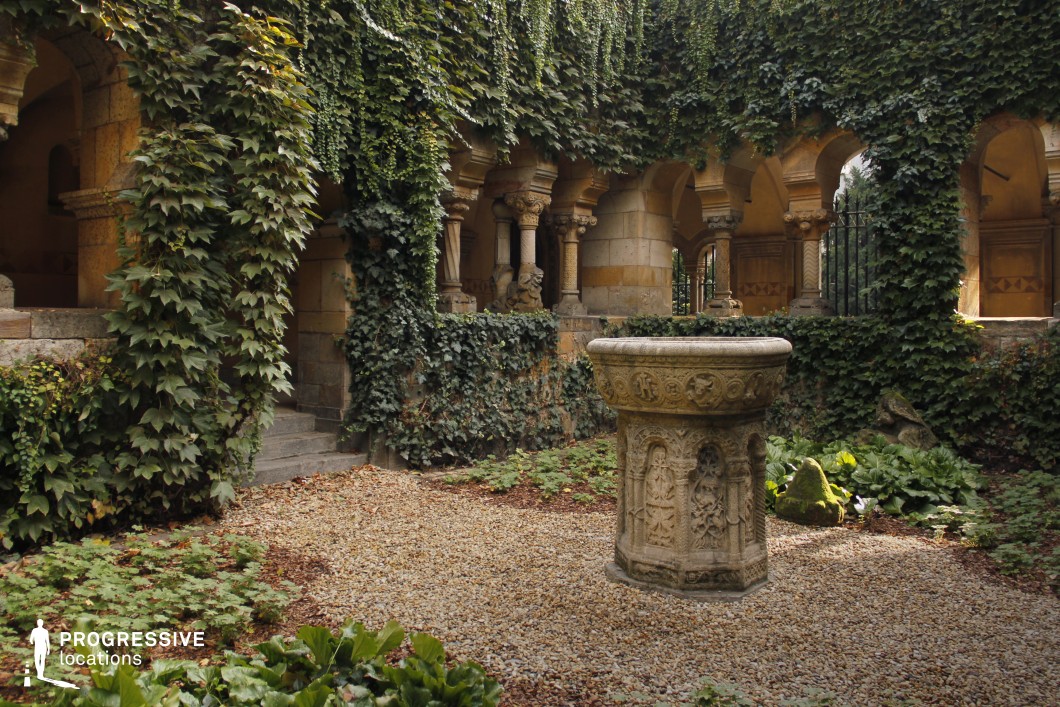 Ivy-covered courtyard with central stone fountain, used for photo and film shoots with arches and enclosed layout