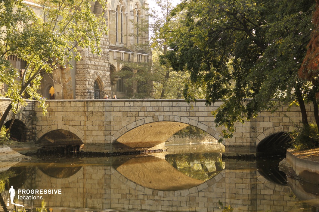 Stone bridge with arches reflected in water, film and photography location with strong symmetry and architectural structure