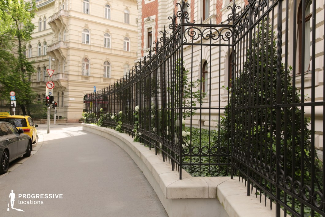 Wrought iron fence along curved street forms a detailed photography and film location with historic architecture backdrop