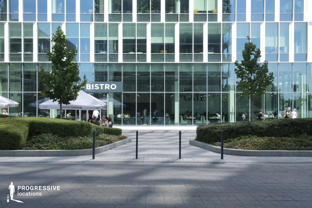 Glass building entrance with bistro and landscaped path, film and photography location with transparent facade