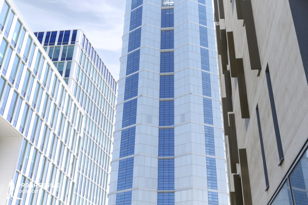 Photography and film location with tall glass tower between modern buildings in urban courtyard