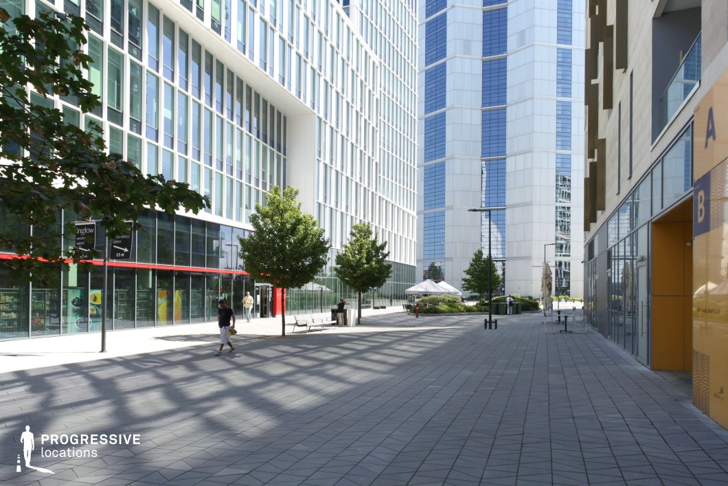 Modern office courtyard with glass façades and paved plaza, ideal location for photography and filming