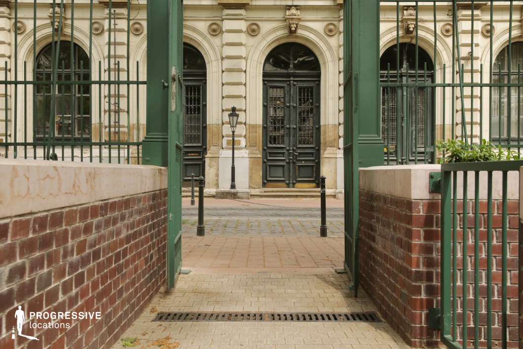 Framed gated entrance with ornate facade beyond serves as a strong photography and film location with symmetrical composition