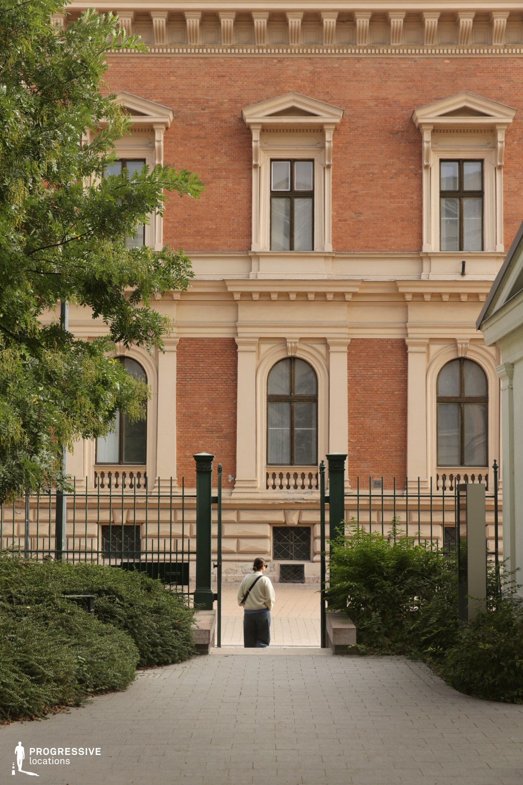 View through gated courtyard toward historic brick facade creates a layered photography and film location with depth