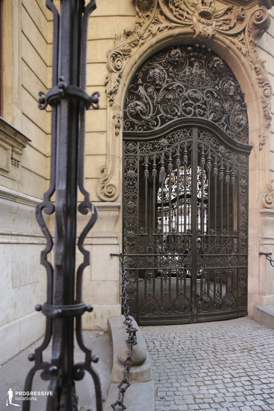 Ornate wrought iron gate within carved stone arch forms a detailed film and photography location with rich textures