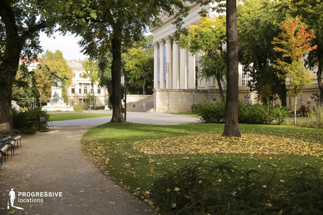 Tree lined park path with classical building backdrop serves as a versatile location for photography and filming