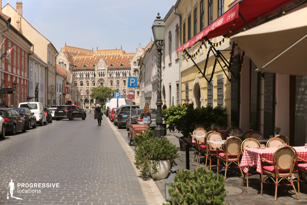 Historic street with café terrace and patterned roof building, ideal film and photography location