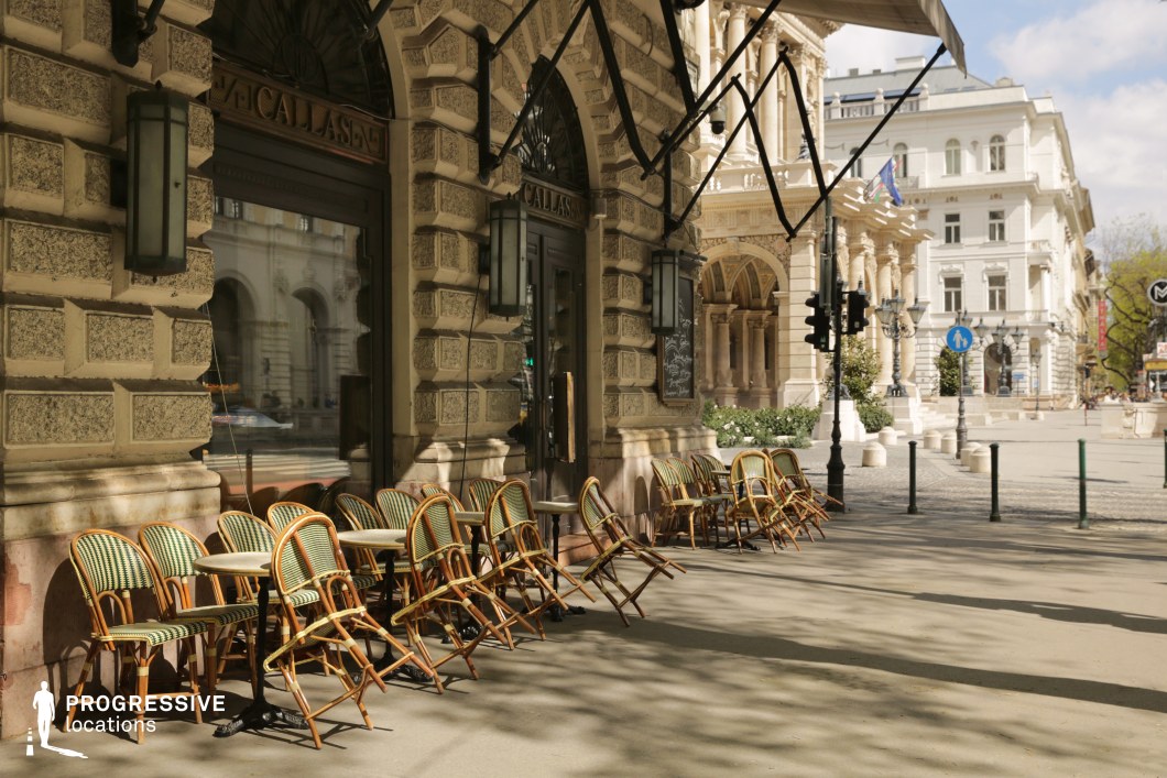Sidewalk cafe beside a historic opera facade available for filming or photo shoots in an elegant city setting.
