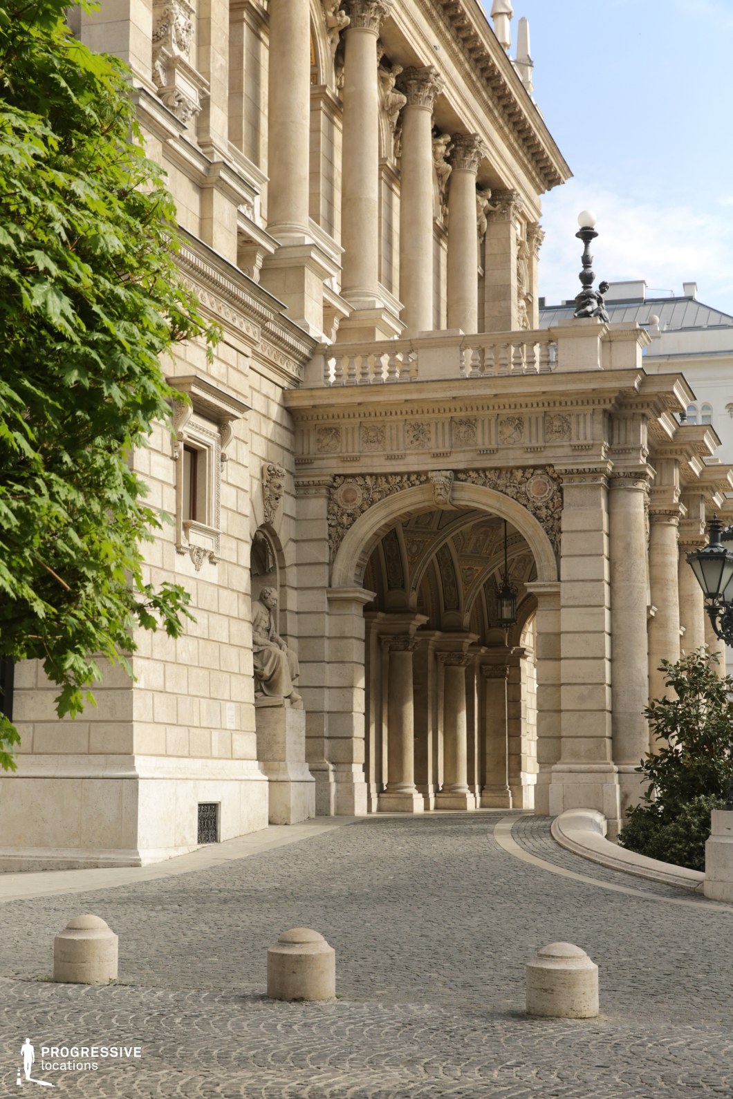 Monumental opera arcade and curved cobblestone drive form a film and photography location with grand architecture.