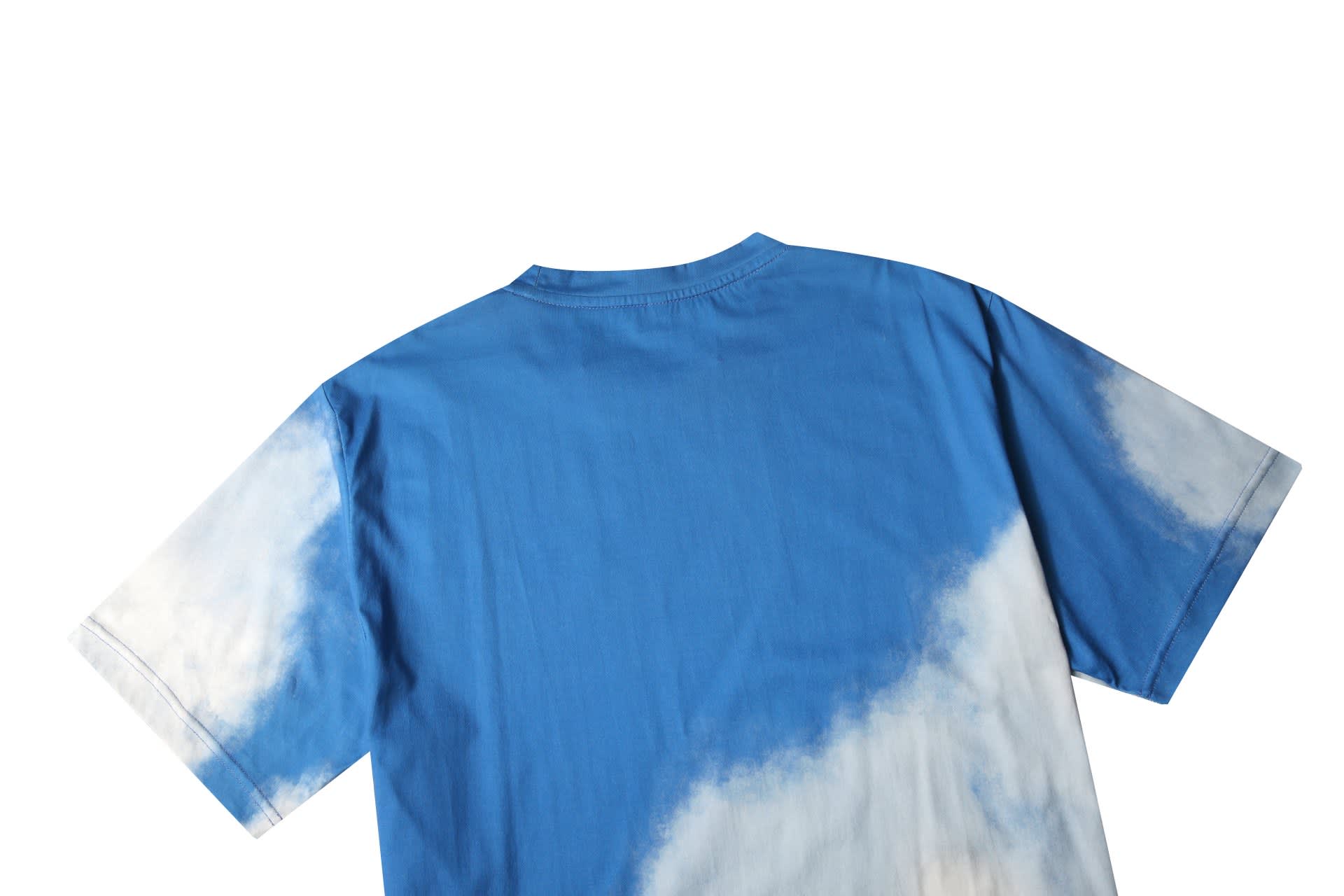 A blue cotton tee featuring a cloud-like design on the back. It has a logo on the garment.