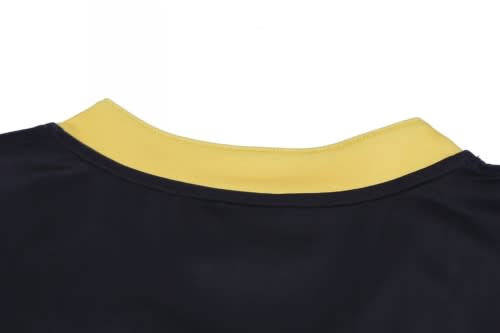 A rugby top featuring a yellow collar and primarily black fabric. It has a logo on the front.