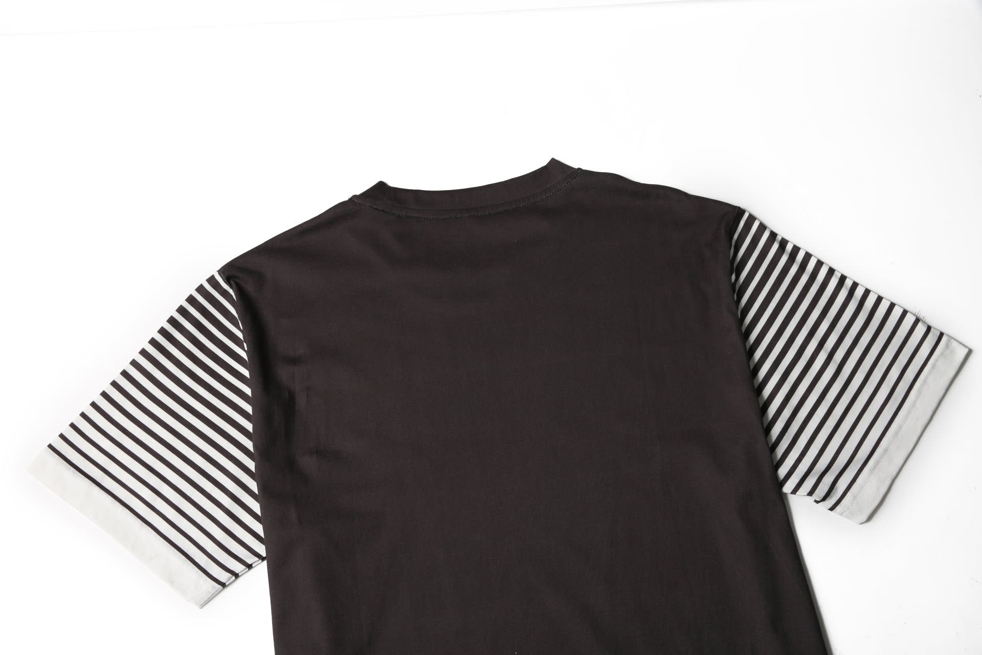 A black t-shirt with striped grey and white sleeves, featuring a logo on the back.