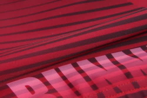 A close-up of a red sports uniform featuring bold black stripes and a branding logo.