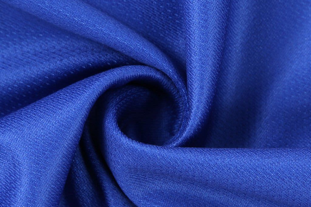 A blue fabric with a smooth texture and subtle weave, featuring a spiral fold.