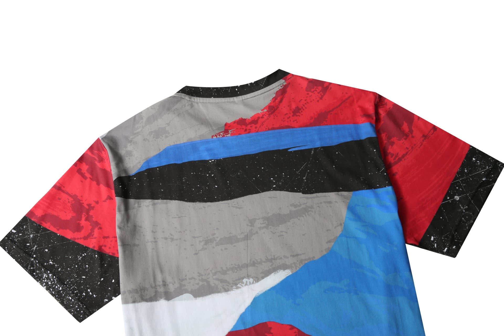 A cotton tee featuring a bold abstract design in red, blue, grey, and black, with a logo on the back.