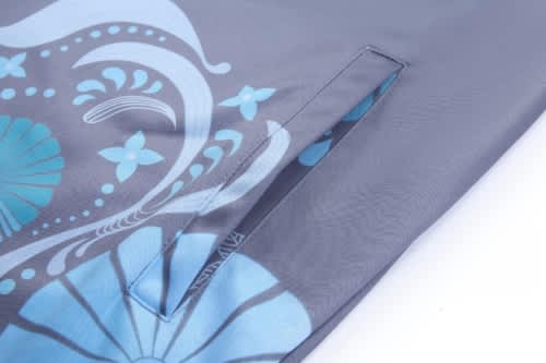 A grey sports jumper features a blue floral design and includes a pocket opening. It has a logo on the fabric.