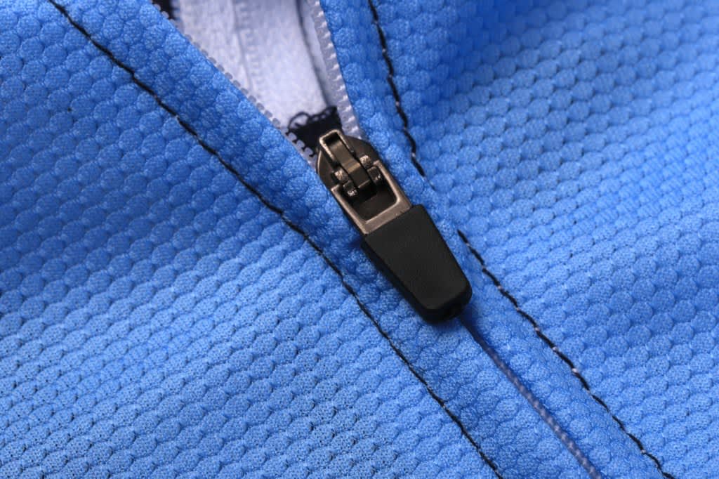 A close-up of a blue sublimated cycling team wear tee featuring a zipper and textured fabric.