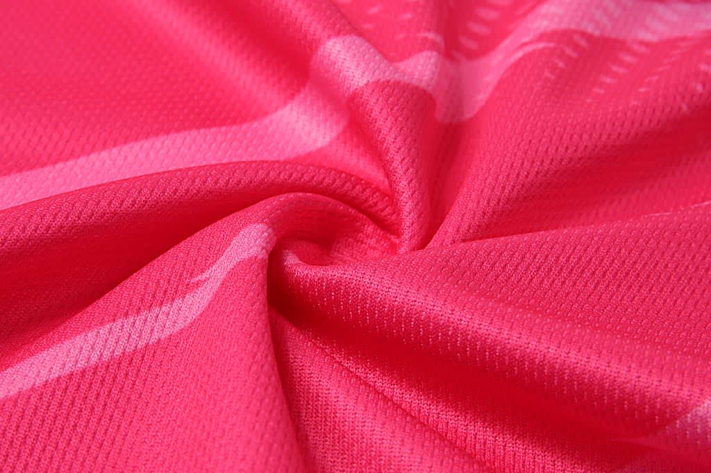 A close-up of a fabric in a vibrant pink colour, featuring a textured pattern. The fabric appears lightweight and smooth.