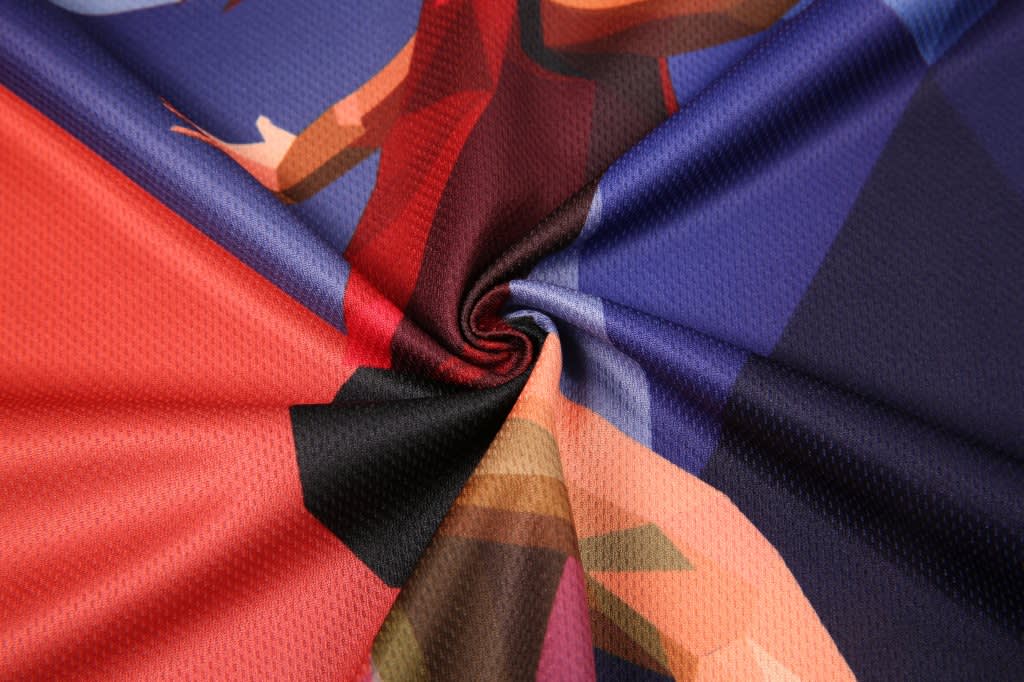 A close-up of a textured fabric featuring vibrant colours, including red, blue, and purple, with a logo present.