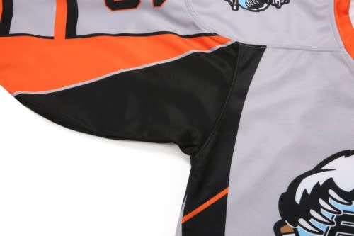 A grey ice hockey jersey featuring black and orange accents with a logo on the sleeve.