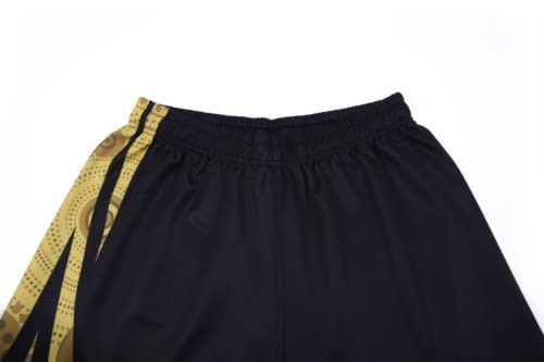 Black sports shorts with a patterned gold side stripe and an elastic waistband. Features a logo.