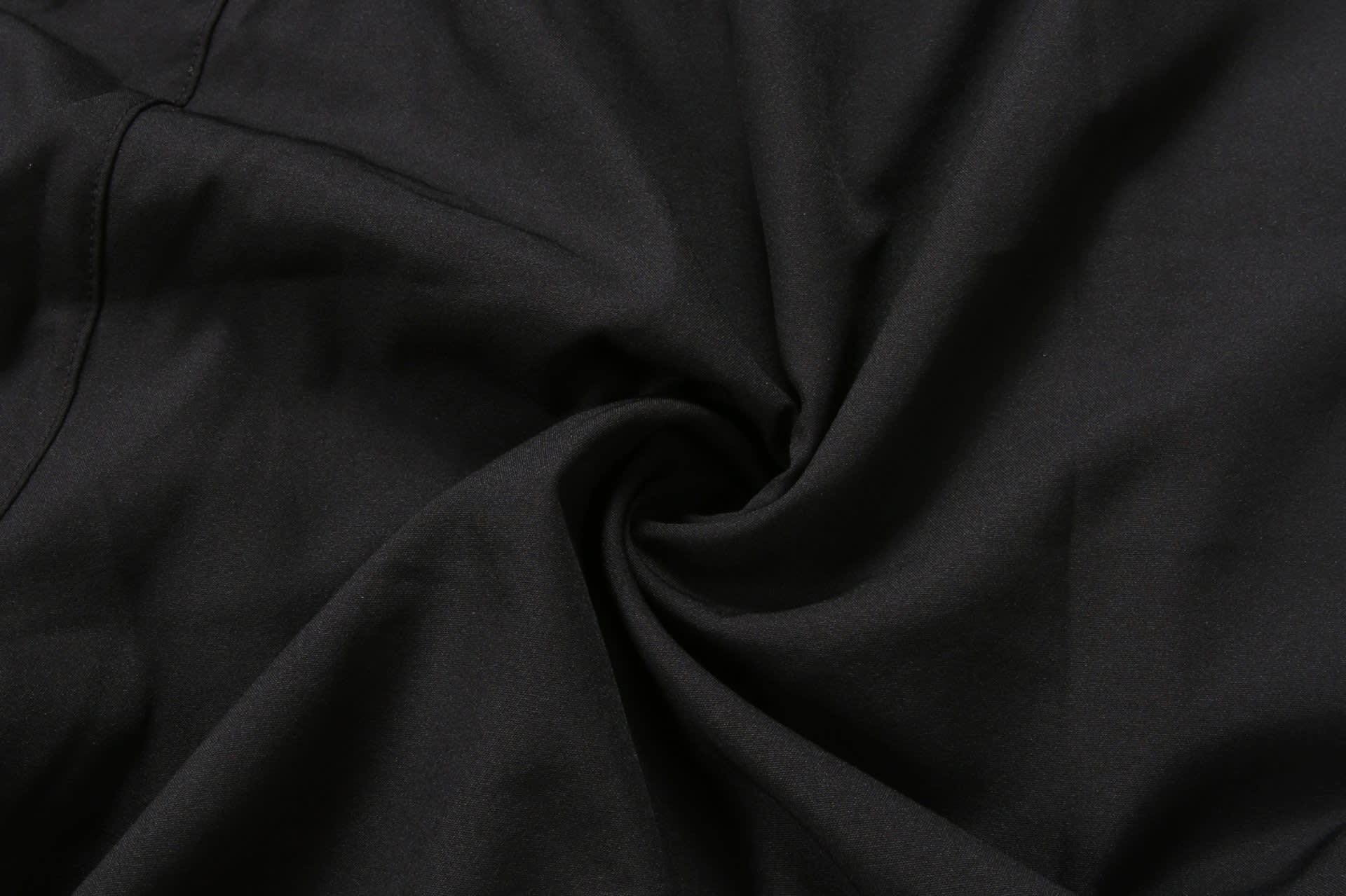 Black school wear shorts displayed in a twisted fabric arrangement, highlighting the material texture.
