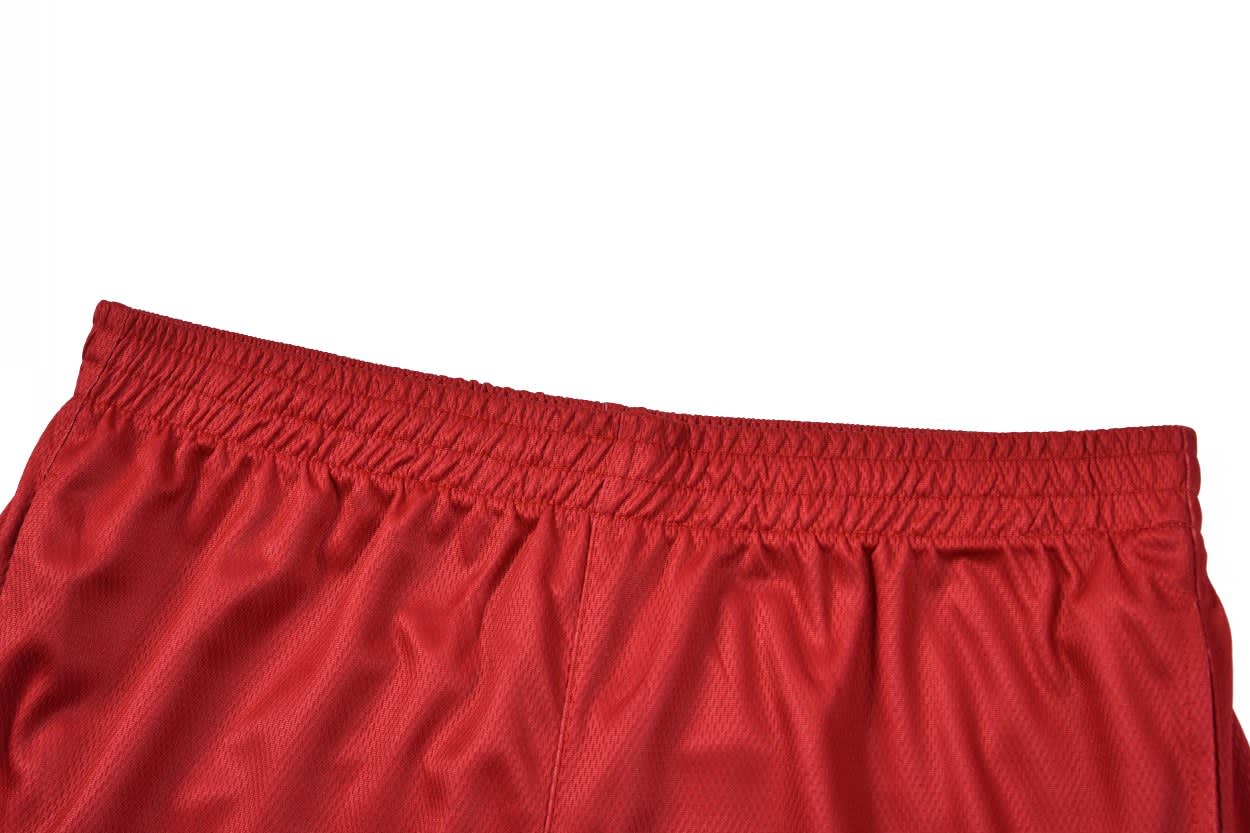 Red tracksuit bottoms with an elasticated waistband and a smooth texture, featuring a logo on the fabric.
