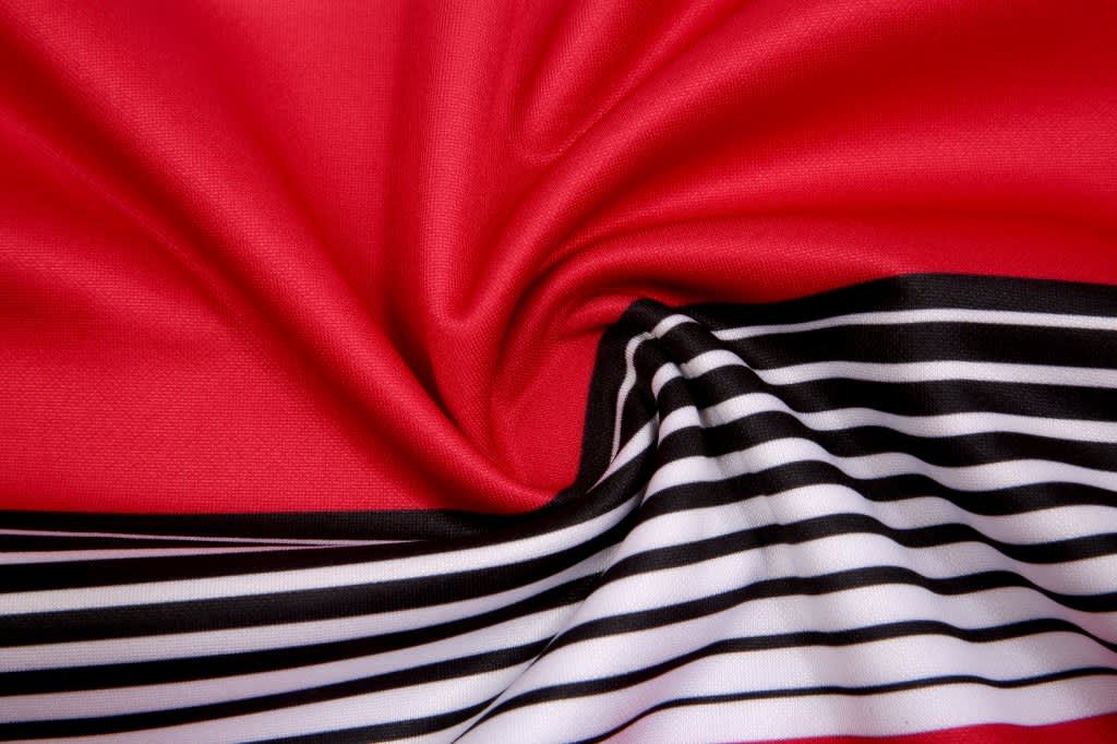 A red fabric with a smooth texture, featuring black and white stripes along one edge.
