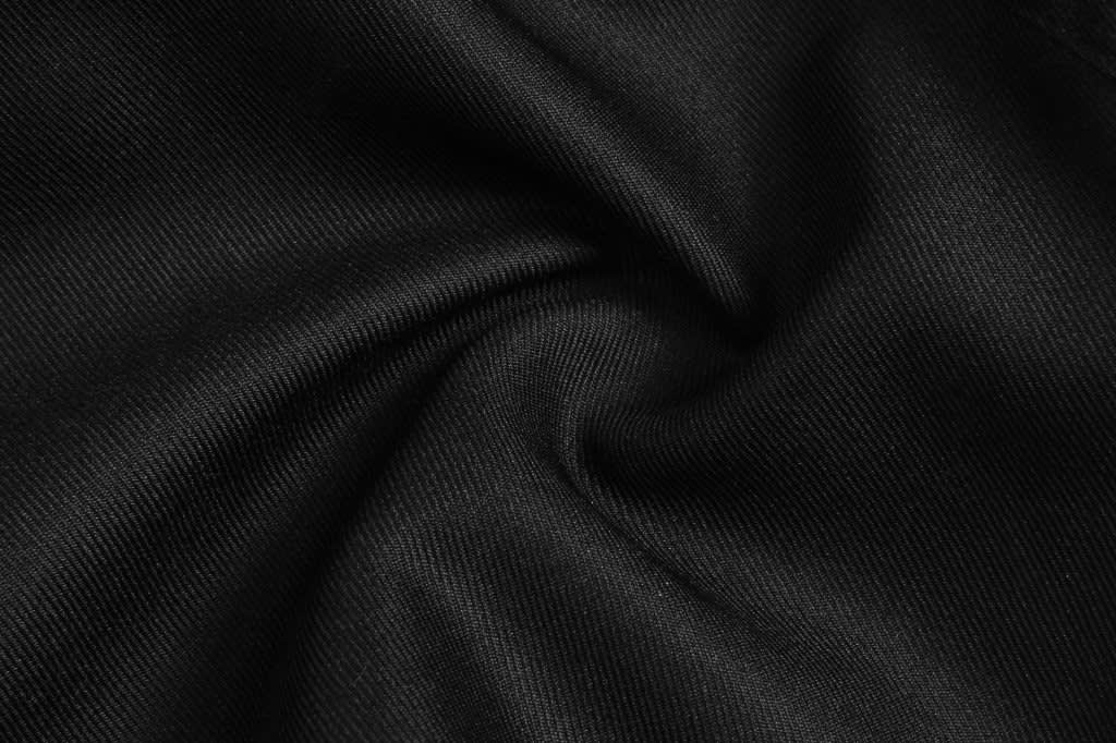 A close-up of black ripstop fabric, showcasing its textured weave and smooth finish, with a logo visible.