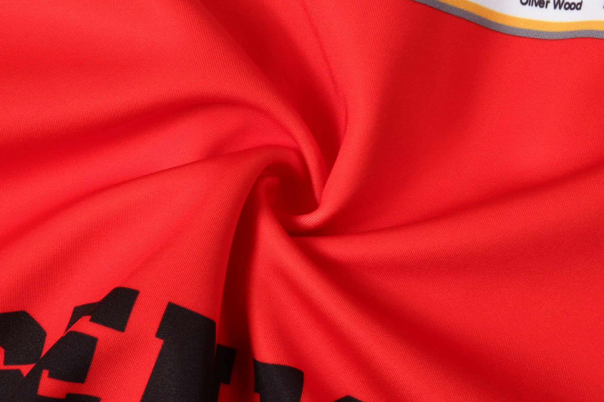 A red sports hoodie featuring a smooth, folded fabric with black lettering and a logo.