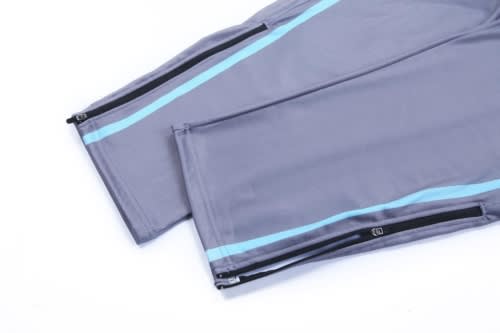 Grey training zip pants featuring light blue detailing and zippers at the ankles. Suitable for sports uniforms.
