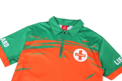 A quarter zip uniform top featuring orange and green colours with a logo and branding.