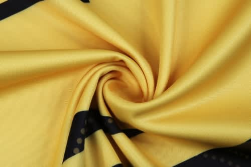 A yellow fabric with black stripes, featuring a swirling pattern, ideal for sports uniforms.