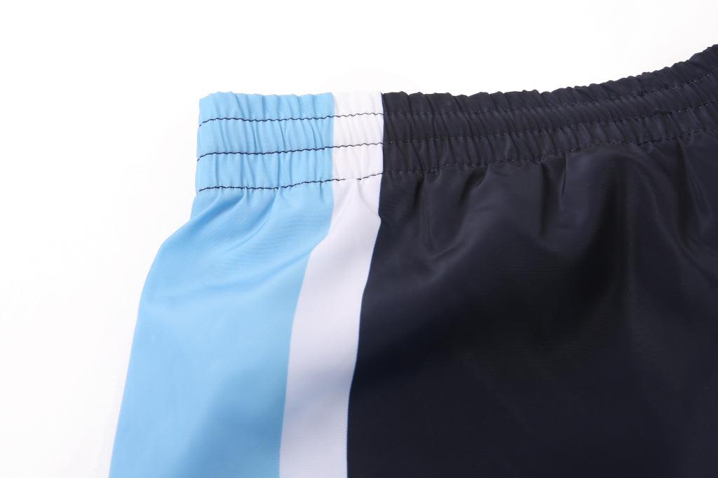 A close-up of black pants with blue and white stripes along the waistband, featuring an elastic band.