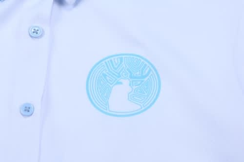 A light blue shirt featuring a circular logo in a similar tone. The shirt has a polo neck and button closure.