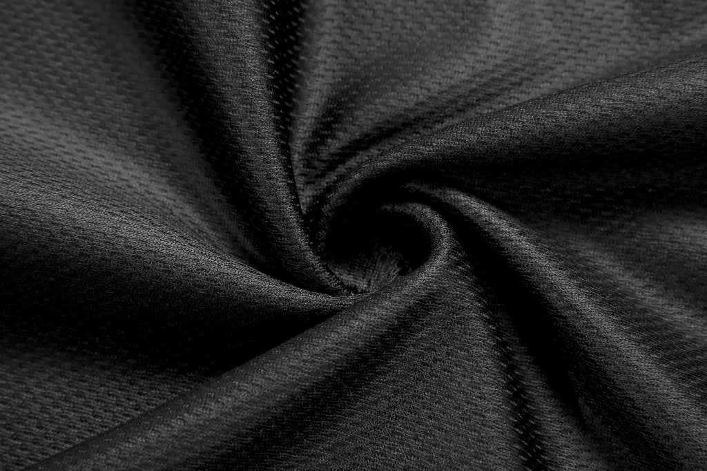 A close-up of black fabric showing a textured pattern, suitable for athletic wear like volleyball shorts.