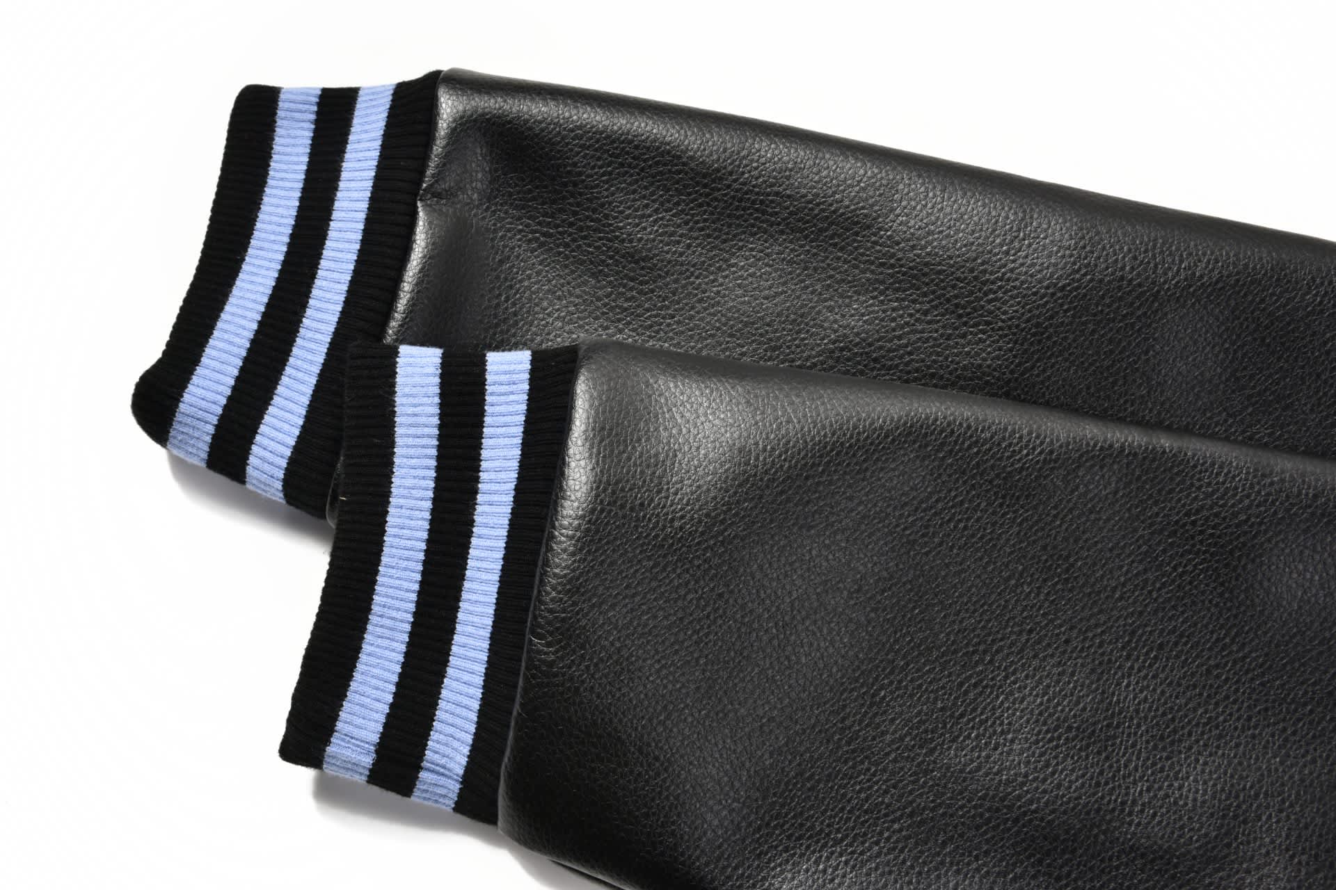 A pair of black PU sleeves with blue and black striped cuffs. The design features a classic athletic style.