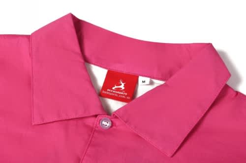 A pink women's beach shirt featuring a collar and a button. It has a label showing brand information.