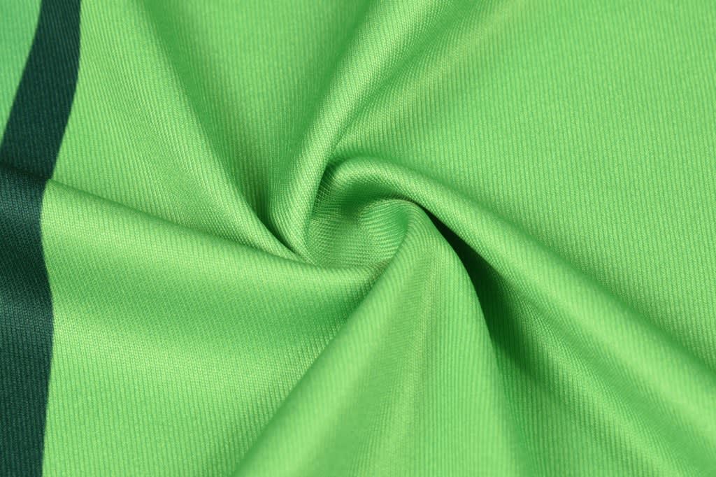 A green fabric with a textured weave, featuring subtle stripes. The material is smooth and lightweight.