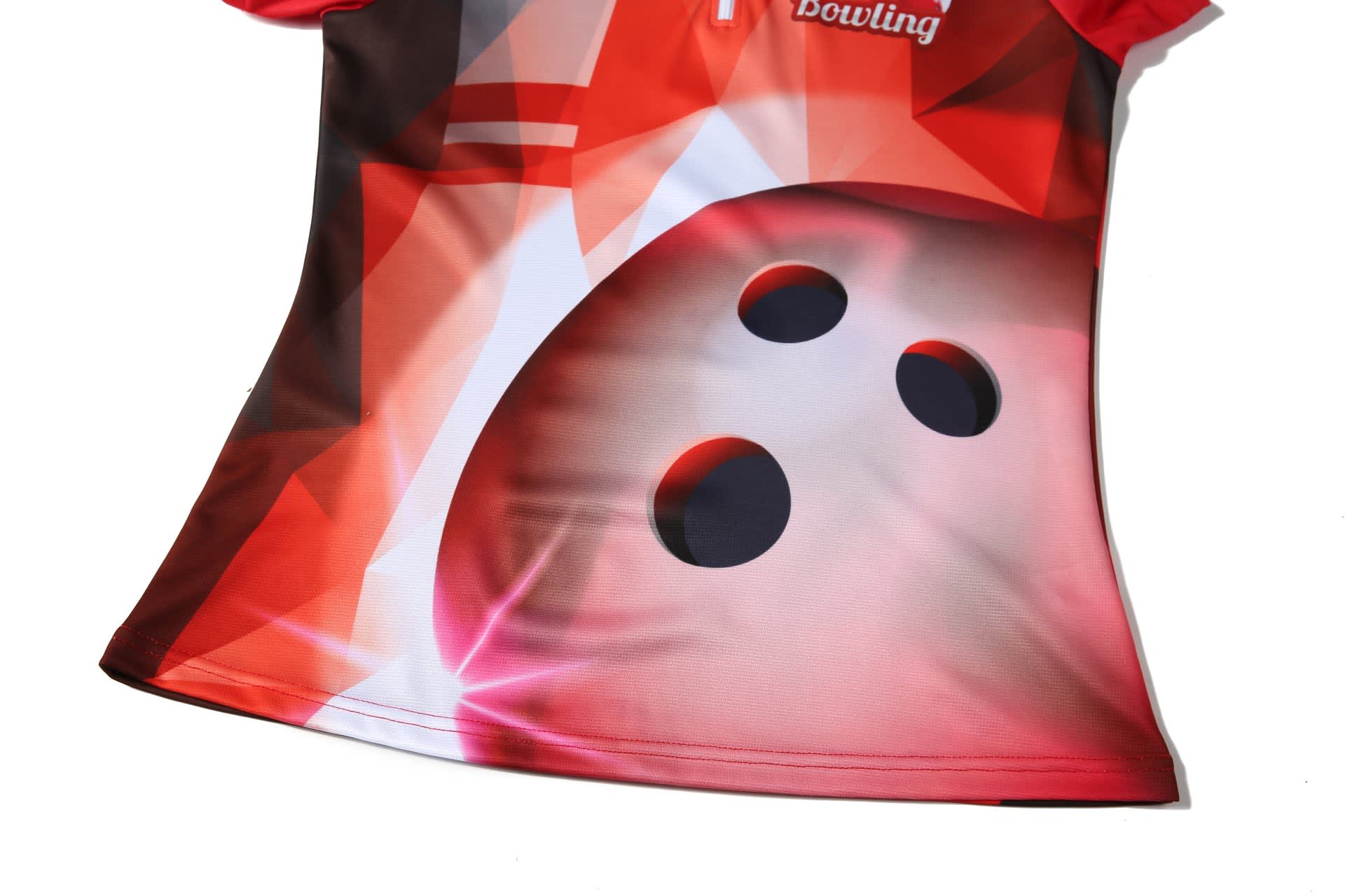 A red bowling team shirt featuring a graphic of a bowling ball with three holes, accented with a geometric design.