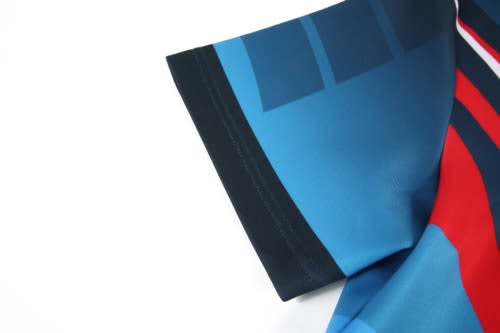 A close-up of a rugby jersey featuring a blue, red, and black design with a logo on the fabric.