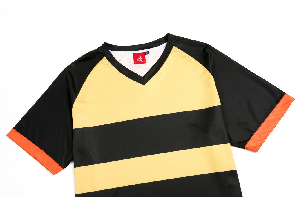 A custom design team t-shirt featuring black, gold, and orange colours with a v-neck and a logo.