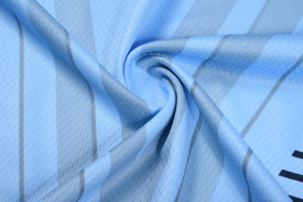 A light blue round neck tee made from soft fabric, featuring a textured pattern and a logo.