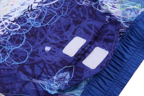 A vibrant blue beach shirt and shorts featuring abstract patterns, with a label area visible.