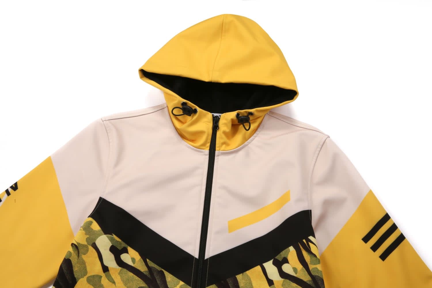 A hooded jacket featuring a yellow and beige design with camouflage patterns and a logo.