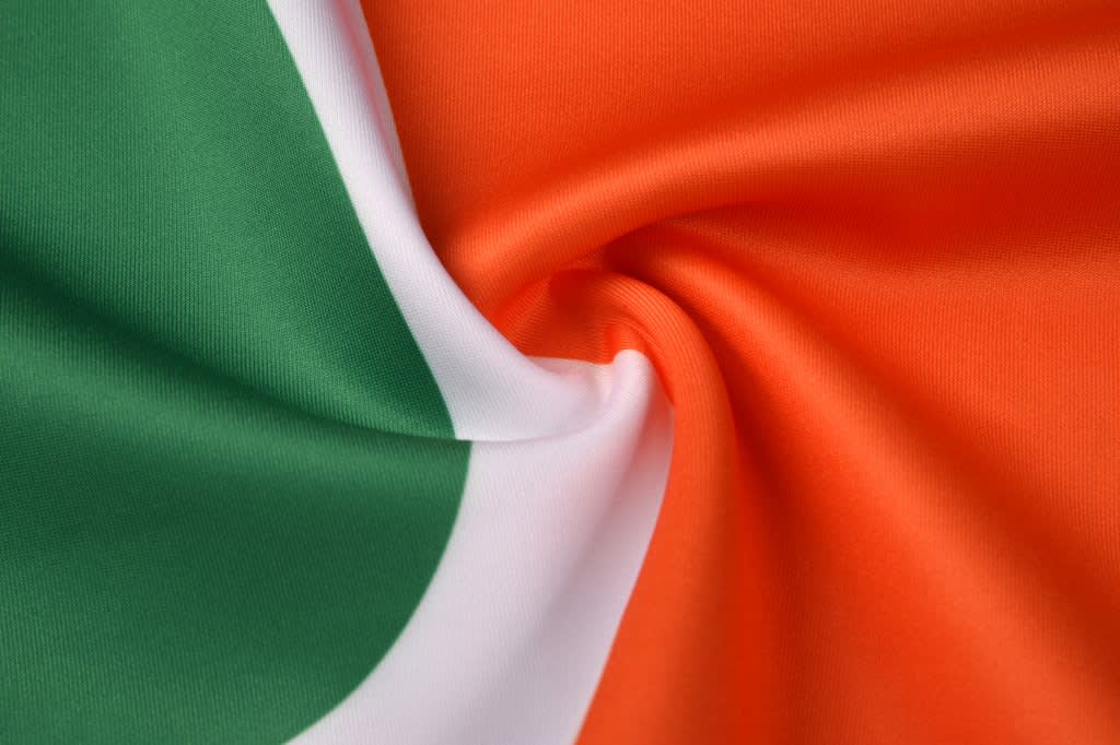 A fabric featuring a combination of green, white, and orange, arranged in a wave pattern.