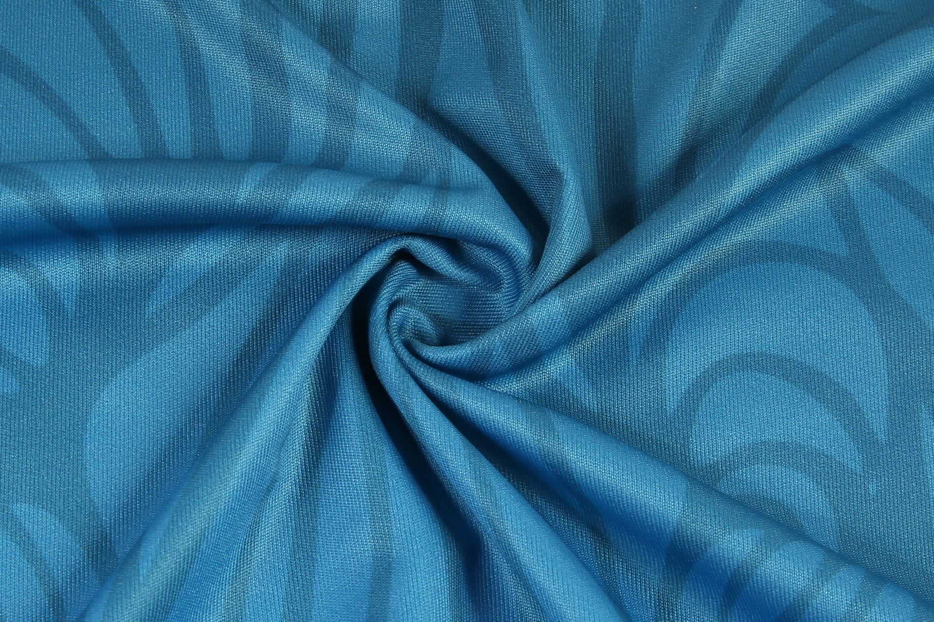 A textured fabric in shades of blue, featuring a swirl pattern, suitable for sportswear.