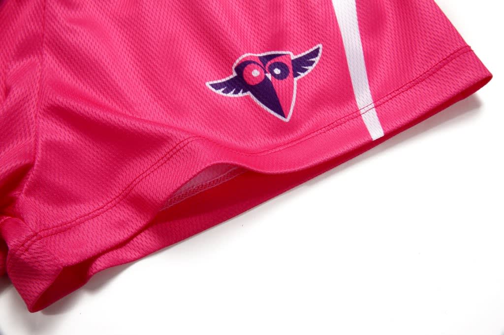 Pink volleyball shorts featuring a logo and white stripe details.