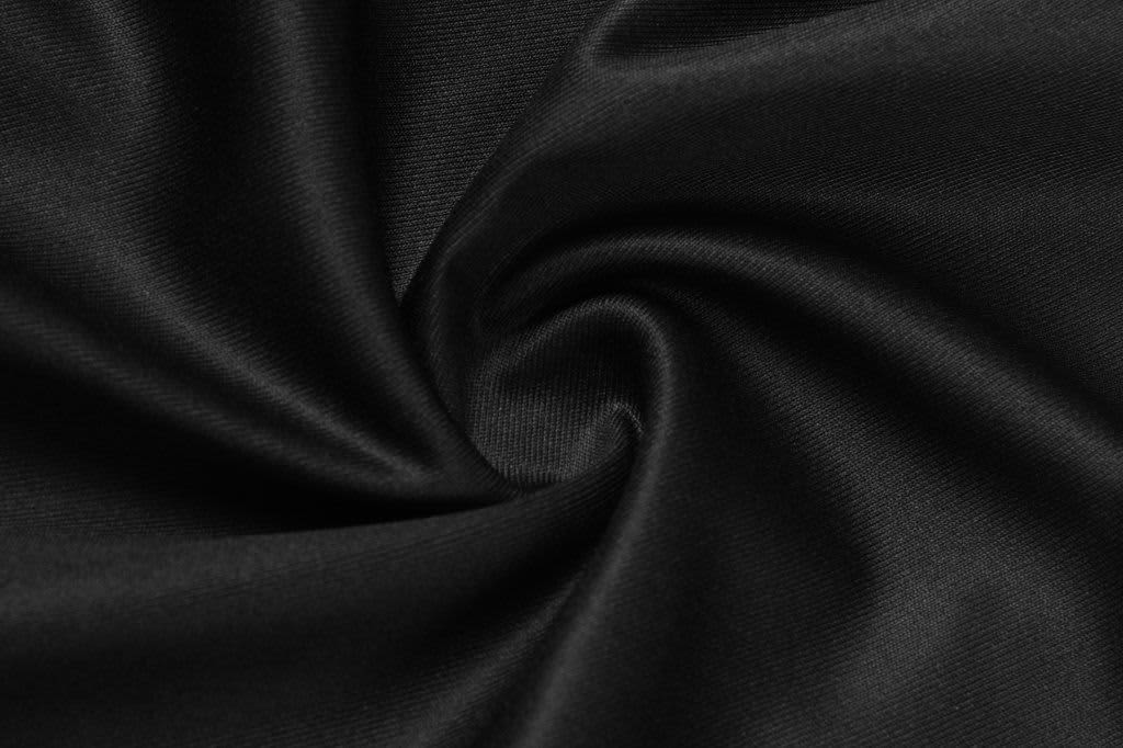A close-up of black fabric, displaying a smooth texture and a swirling pattern. The material appears lightweight and flexible.